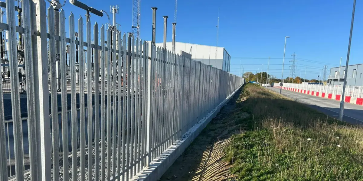 Galvanised palisade fence along an industrial boundary